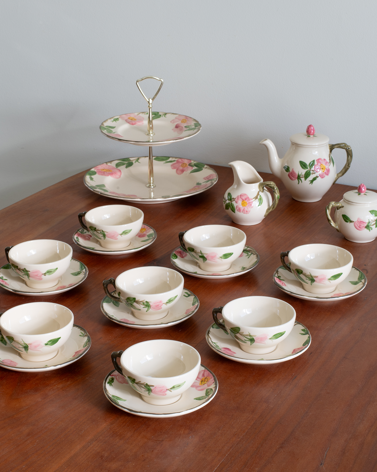 A coordinated porcelain tea or coffee set arranged on a wooden table against a light gray wall.