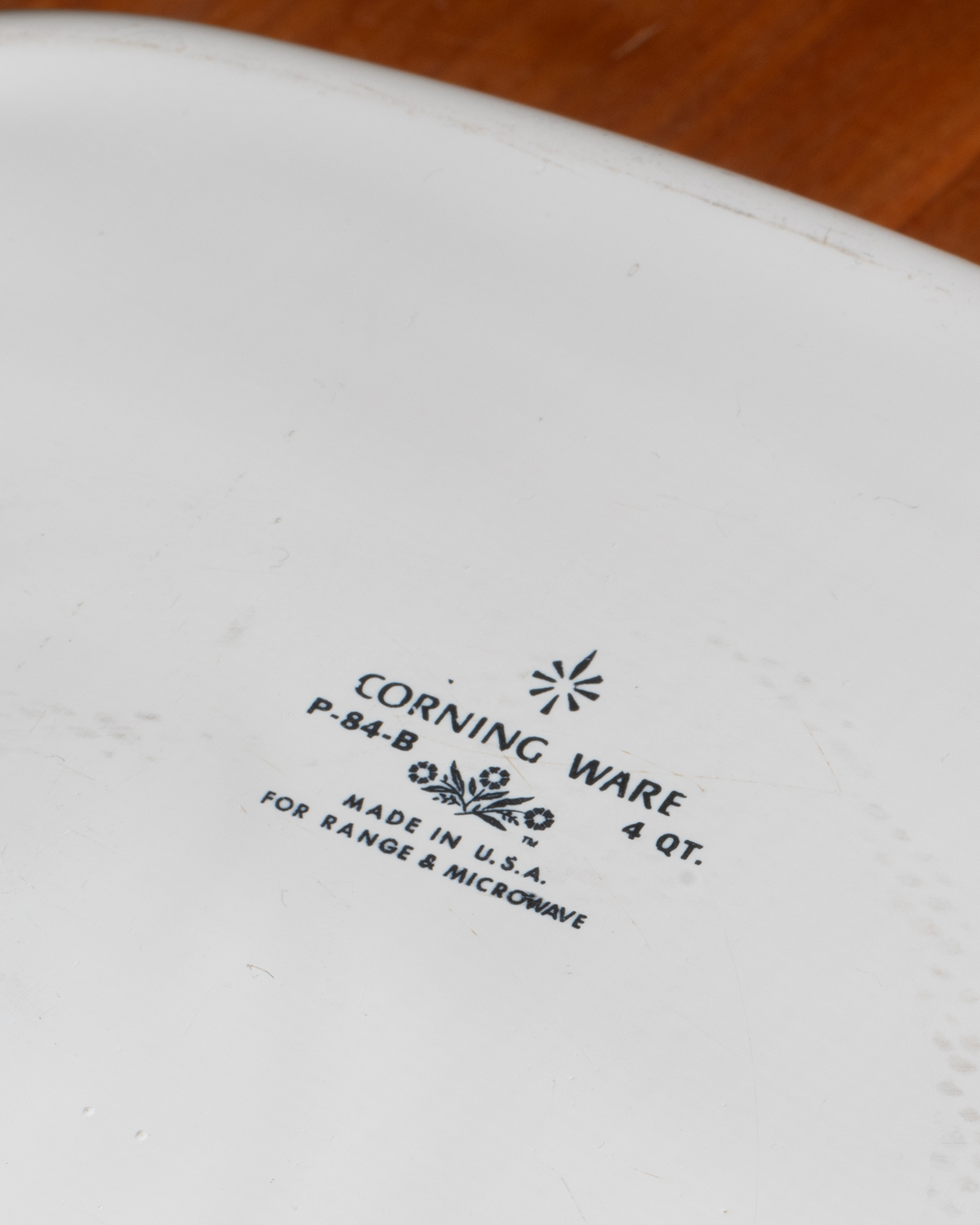 Close-up of a white ceramic Corning Ware 4-quart range and microwave oven dish, showing the black printed model number P-84-B and manufacturer text.