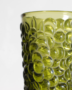 Close-up of a translucent olive green glass container with a textured, bubble-like embossed pattern on a white background.