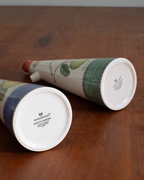 Two Wedwoodwood ceramic garden planters shaped like conical flower pots, displayed on a wooden tabletop. One planter is lying on its side showing the white base with the Wedwoodwood brand name, and the other is angled to show its green and blue patterned upper body.