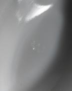 A close-up of a glossy, light gray surface with a bright reflection and a small, faint logo or mark in the center.