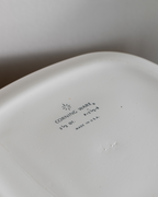 Close-up of the inside bottom of a white ceramic dish or plate, showing printed text that reads CORNING WARE with a small starburst logo, along with size and made-in-USA information.