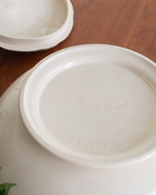 Close-up of the inside bottom of a white ceramic toureen, showing the embossed brand name 'Franciscan' and 'MADE IN ENGLAND' on a wooden table.